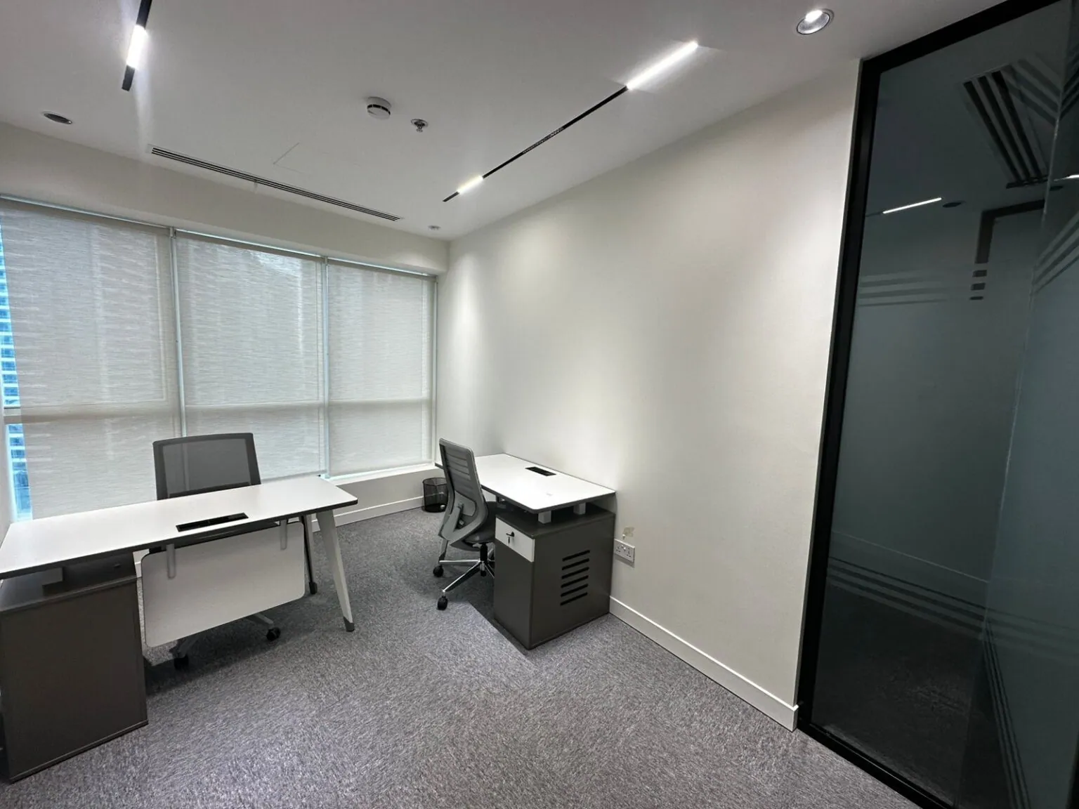 A dedicated desk in the Privé Lounge shared workspace, with task lighting and window seating